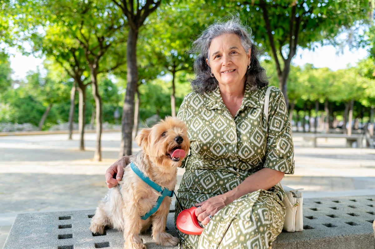 Elderly woman with small dog in park