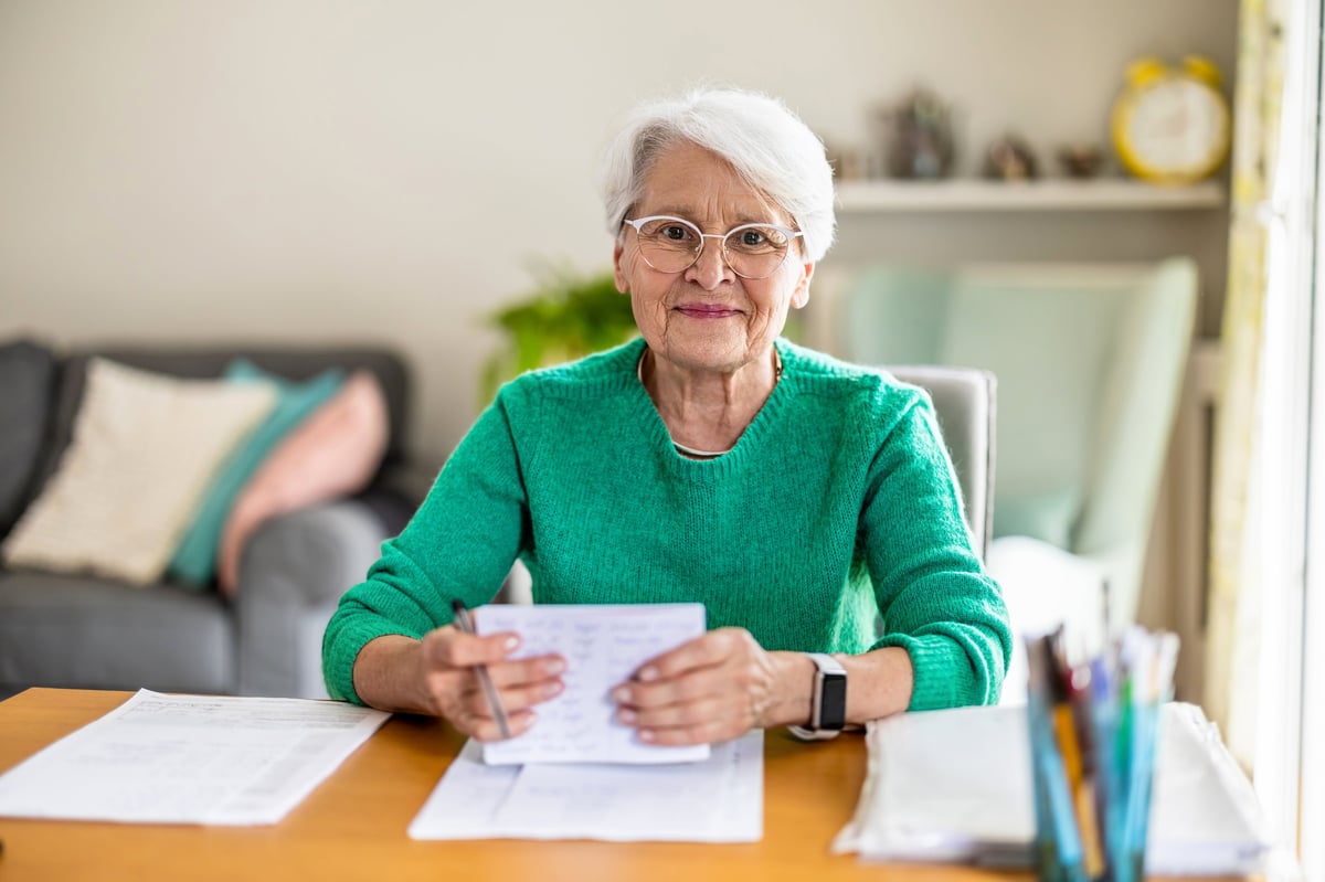 Senior woman sitting in the living room and doing paperwork