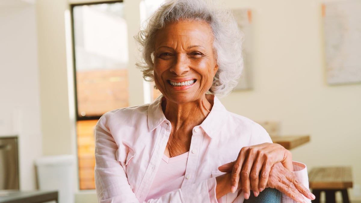 Portrait Of Smiling Senior Woman Sitting On Sofa At Home Together