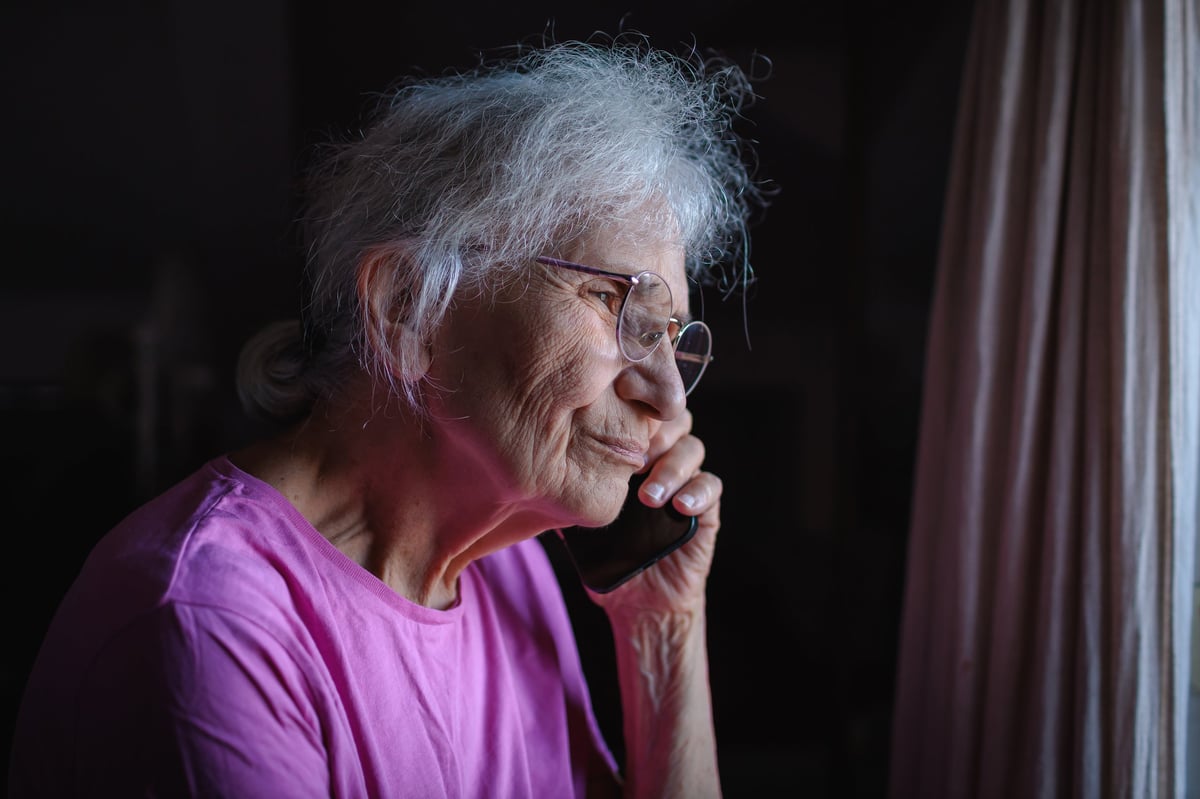 Elderly woman enjoys a heartfelt conversation on the phone during the evening in a cozy living room