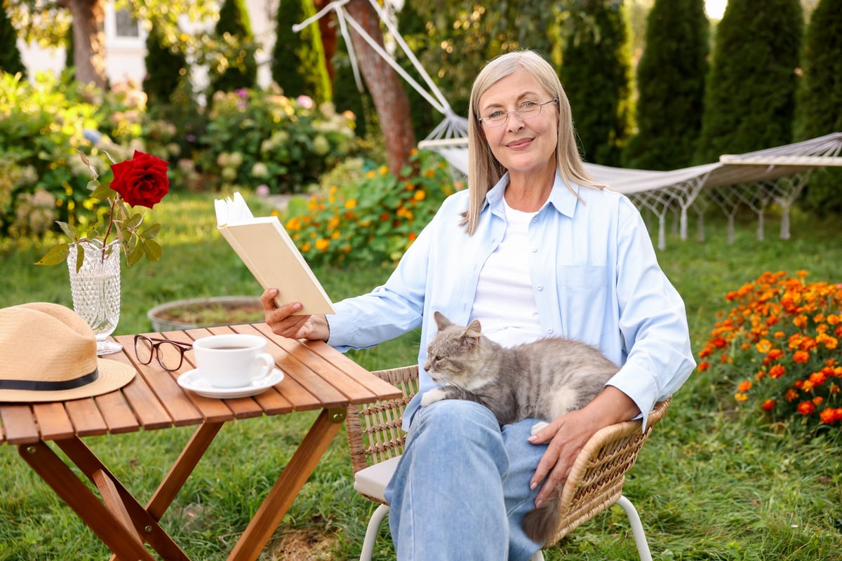 Senior woman with cat reading book